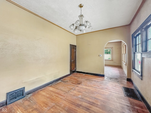 1011 W 7th St, Anderson, IN 46016 - empty room with arched walkways, crown molding, a textured ceiling, a chandelier, and wood finished floors