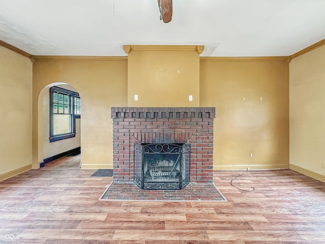 1011 W 7th St, Anderson, IN 46016 - unfurnished living room featuring crown molding, wood finished floors, a fireplace, and arched walkways