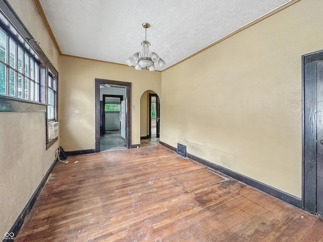 1011 W 7th St, Anderson, IN 46016 - unfurnished dining area with arched walkways, crown molding, wood finished floors, a chandelier, and a textured ceiling
