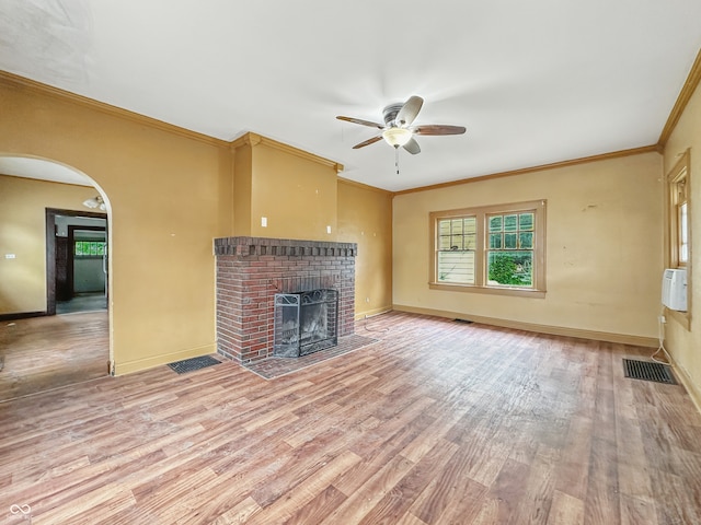 1011 W 7th St, Anderson, IN 46016 - unfurnished living room featuring ceiling fan, wood finished floors, a brick fireplace, crown molding, and arched walkways