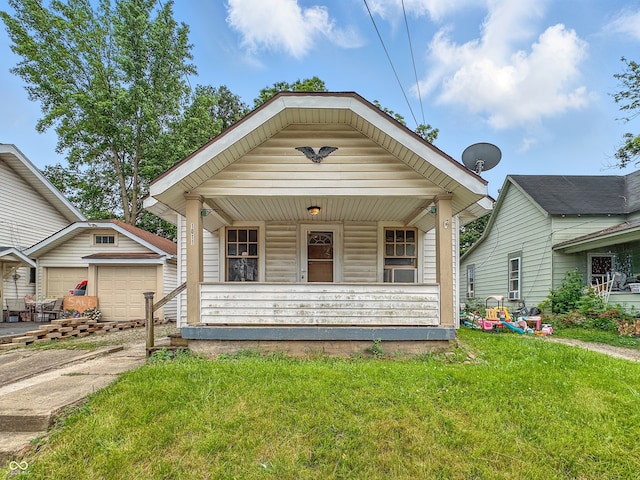 1011 W 7th St, Anderson, IN 46016 - view of front of property with covered porch, a front yard, concrete driveway, and a garage
