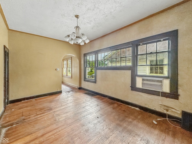 1011 W 7th St, Anderson, IN 46016 - unfurnished room with a chandelier, ornamental molding, hardwood / wood-style flooring, a textured ceiling, and arched walkways