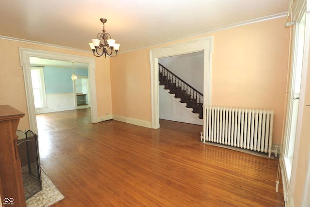 611 E Wabash Ave, Crawfordsville, IN 47933 - unfurnished room featuring radiator, wood finished floors, a chandelier, crown molding, and stairway