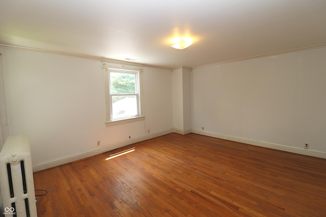 611 E Wabash Ave, Crawfordsville, IN 47933 - unfurnished room featuring radiator heating unit, light wood-type flooring, and crown molding