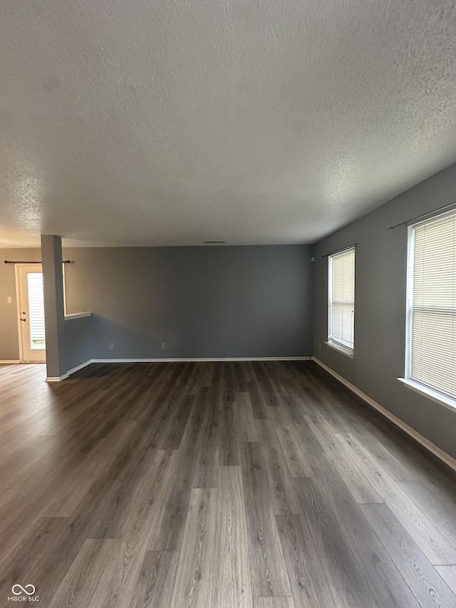 12639 Justice Xing, Fishers, IN 46037 - unfurnished living room with a textured ceiling, dark wood finished floors, and plenty of natural light