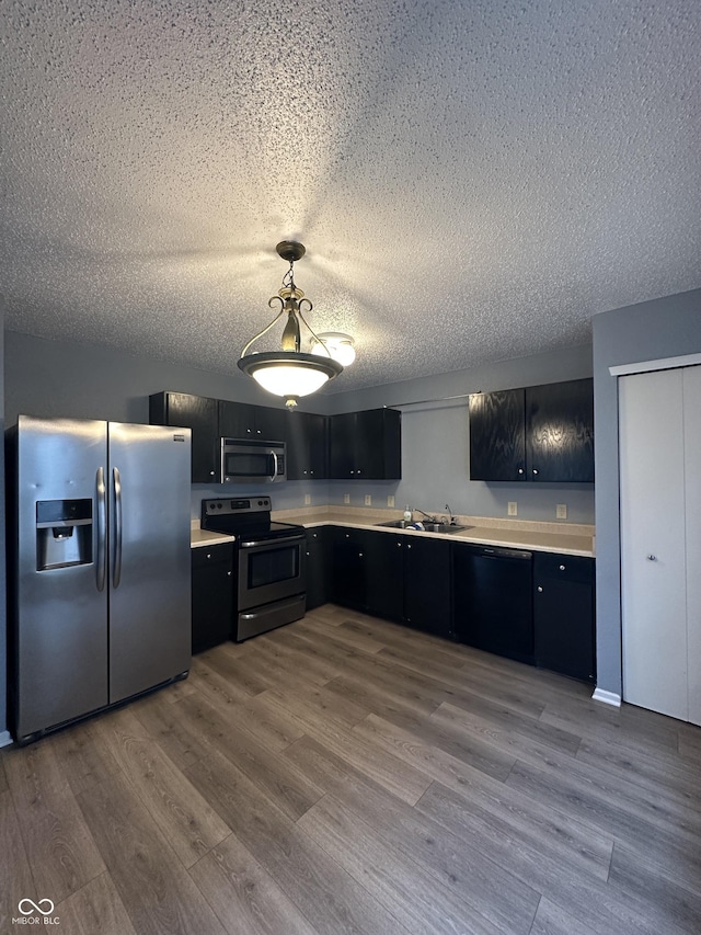 12639 Justice Xing, Fishers, IN 46037 - kitchen featuring appliances with stainless steel finishes, dark cabinetry, light countertops, a textured ceiling, and wood finished floors