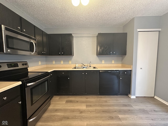 12639 Justice Xing, Fishers, IN 46037 - kitchen with stainless steel appliances, a textured ceiling, light countertops, light wood-type flooring, and dark cabinetry