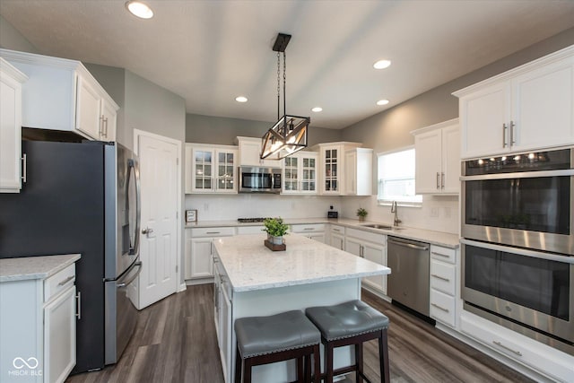 10334 Deercrest Ln, Indianapolis, IN 46239 - kitchen with stainless steel appliances, a kitchen island, white cabinets, dark wood-style floors, and tasteful backsplash