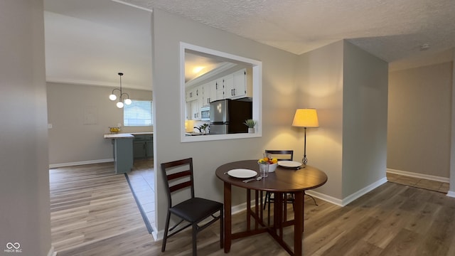 3019 E Berwyn St, Indianapolis, IN 46203 - dining area with wood finished floors, a textured ceiling, and a chandelier