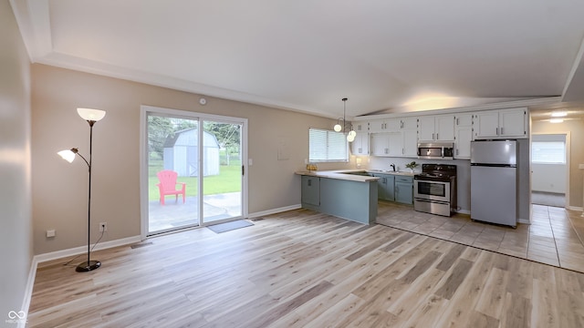3019 E Berwyn St, Indianapolis, IN 46203 - kitchen with appliances with stainless steel finishes, light wood-type flooring, a peninsula, lofted ceiling, and light countertops