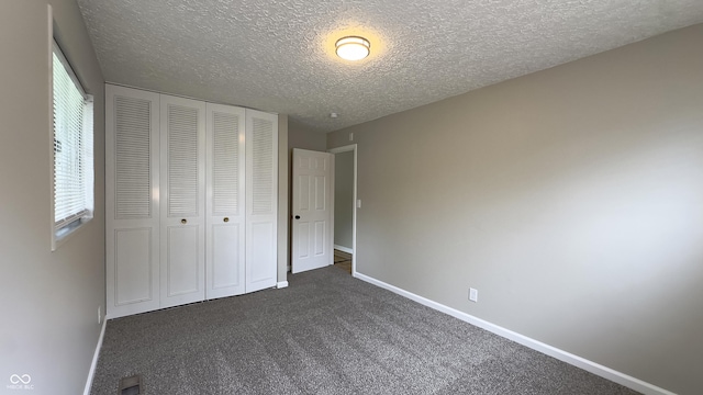 3019 E Berwyn St, Indianapolis, IN 46203 - unfurnished bedroom with dark carpet, a closet, and a textured ceiling