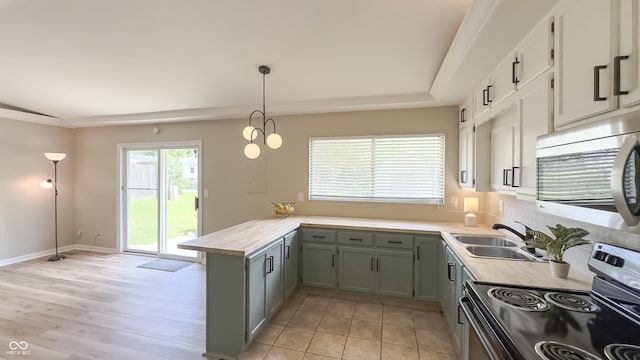 3019 E Berwyn St, Indianapolis, IN 46203 - kitchen with range with electric stovetop, stainless steel microwave, a peninsula, light countertops, and pendant lighting