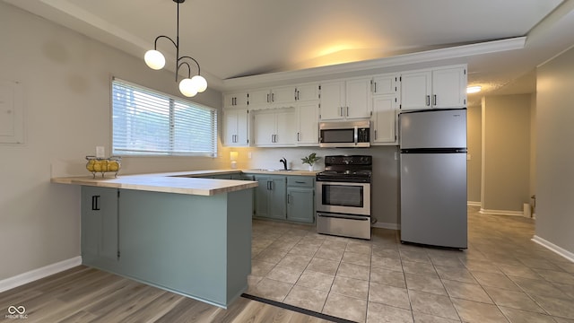 3019 E Berwyn St, Indianapolis, IN 46203 - kitchen with appliances with stainless steel finishes, a raised ceiling, a peninsula, light countertops, and decorative light fixtures
