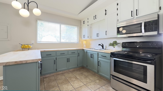 3019 E Berwyn St, Indianapolis, IN 46203 - kitchen with appliances with stainless steel finishes, butcher block counters, white cabinets, light tile patterned floors, and hanging light fixtures