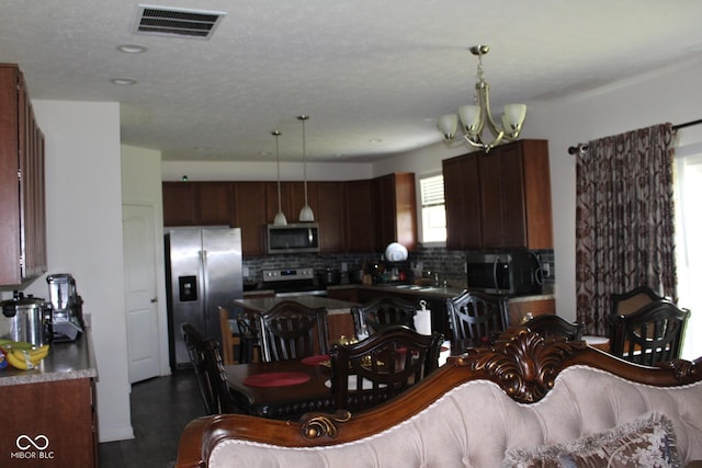 9068 Thames Dr, Avon, IN 46123 - kitchen with appliances with stainless steel finishes, a chandelier, tasteful backsplash, decorative light fixtures, and dark countertops