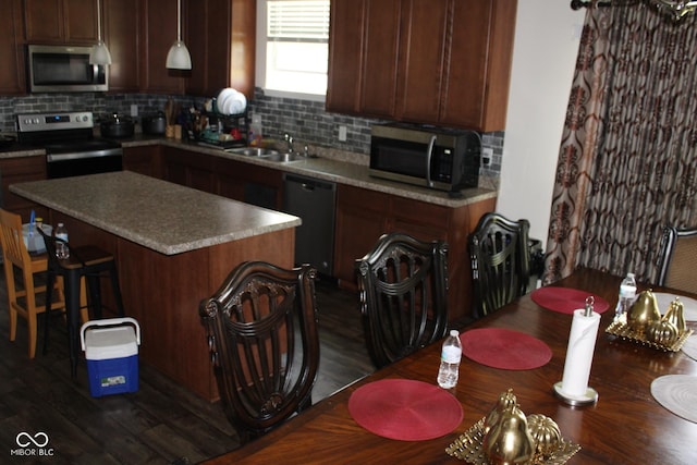 9068 Thames Dr, Avon, IN 46123 - kitchen with appliances with stainless steel finishes, decorative backsplash, a kitchen island, and a breakfast bar area