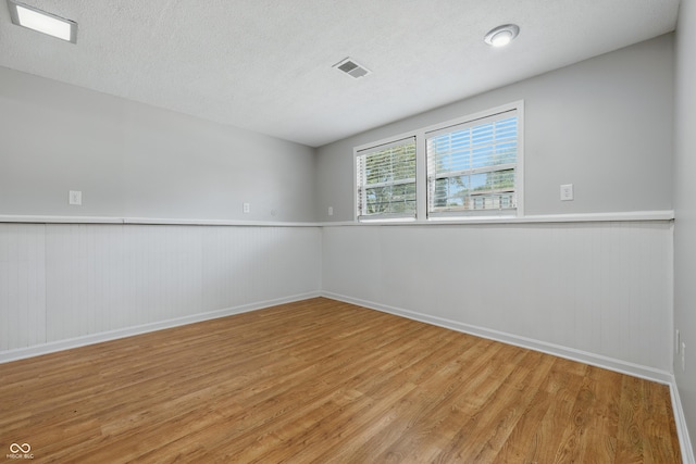 5503 Antoneli Ln, Indianapolis, IN 46237 - spare room with light wood-style flooring, wainscoting, and a textured ceiling
