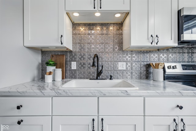 5503 Antoneli Ln, Indianapolis, IN 46237 - kitchen with stainless steel microwave, white cabinetry, decorative backsplash, and light stone countertops