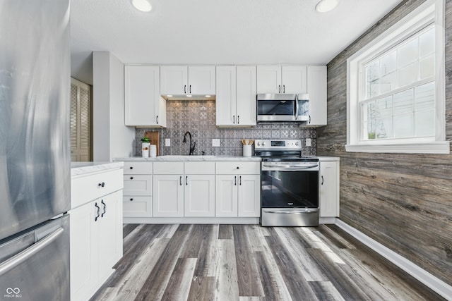 5503 Antoneli Ln, Indianapolis, IN 46237 - kitchen featuring stainless steel appliances, white cabinets, decorative backsplash, wood finished floors, and wooden walls