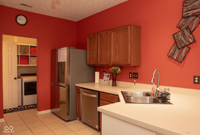 6585 Dunsdin Dr, Plainfield, IN 46168 - kitchen with stainless steel appliances, washer / clothes dryer, light countertops, light tile patterned floors, and brown cabinets