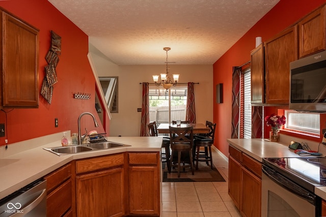 6585 Dunsdin Dr, Plainfield, IN 46168 - kitchen with stainless steel appliances, a chandelier, light tile patterned floors, a peninsula, and light countertops