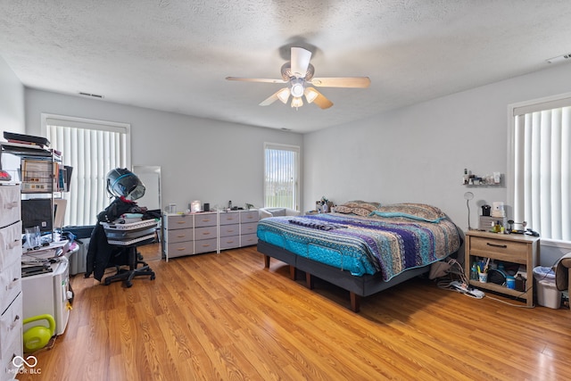 8038 Midlothian Way, Indianapolis, IN 46214 - bedroom with light wood-style floors, a textured ceiling, a ceiling fan, and an office area