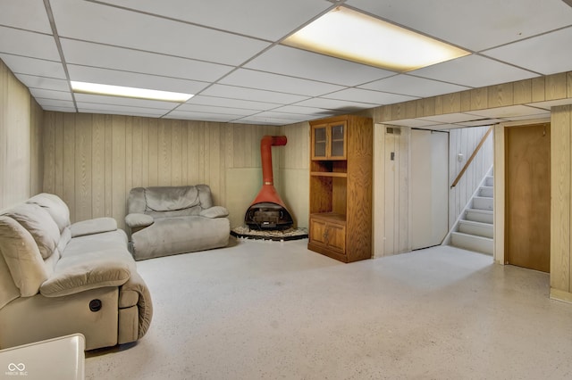 241 Wehmeier St, Columbus, IN 47201 - living room with a wood stove, a paneled ceiling, stairway, speckle patterned floor, and wooden walls