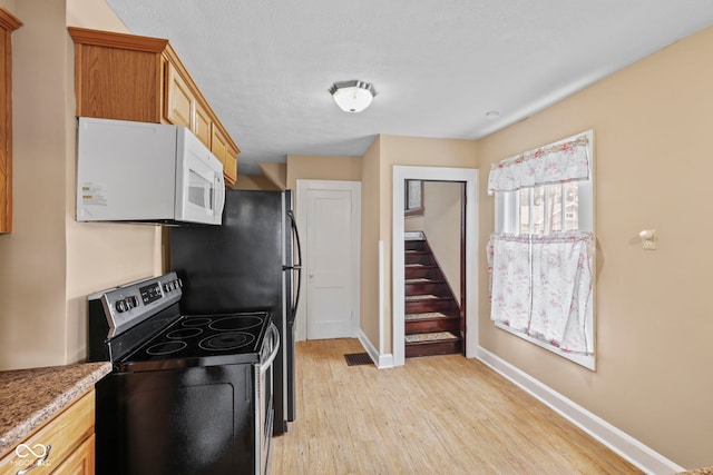 113 N Munsie St, Indianapolis, IN 46229 - kitchen with stainless steel electric stove, white microwave, and light wood-type flooring