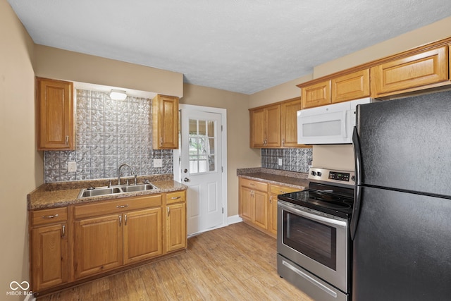 113 N Munsie St, Indianapolis, IN 46229 - kitchen with freestanding refrigerator, stainless steel range with electric cooktop, white microwave, light wood finished floors, and decorative backsplash