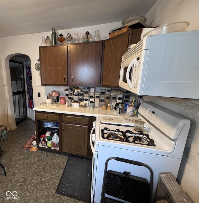 1768 N Lynhurst Dr, Speedway, IN 46224 - kitchen featuring white appliances, arched walkways, light countertops, and dark brown cabinetry