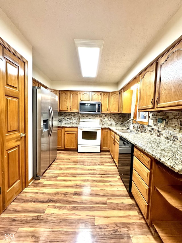 526 Jefferson Vly, Coatesville, IN 46121 - kitchen featuring appliances with stainless steel finishes, light wood-style flooring, brown cabinetry, and tasteful backsplash