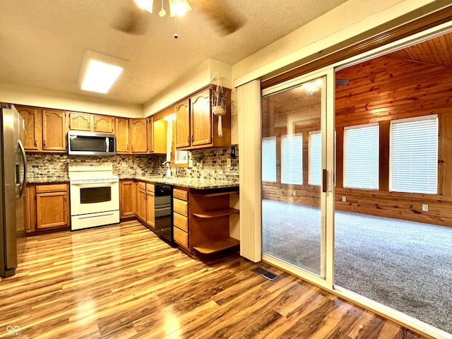 526 Jefferson Vly, Coatesville, IN 46121 - kitchen featuring appliances with stainless steel finishes, brown cabinetry, decorative backsplash, lofted ceiling, and wooden walls