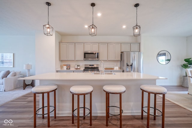 9728 Junction, Fishers, IN 46037 - kitchen with appliances with stainless steel finishes, a center island with sink, light countertops, a kitchen breakfast bar, and dark wood-type flooring