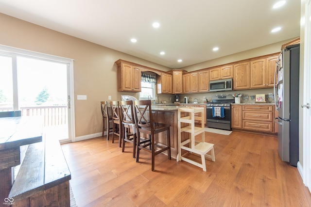 8090 N State Highway 7, Elizabethtown, IN 47232 - kitchen featuring stainless steel appliances, a kitchen bar, light wood finished floors, recessed lighting, and light stone counters