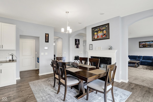 5812 Flat Hill Dr, Indianapolis, IN 46239 - dining area featuring arched walkways, dark wood finished floors, a glass covered fireplace, and a chandelier