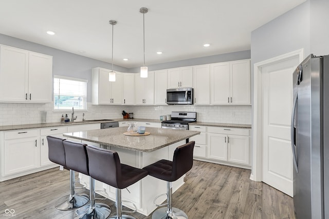5812 Flat Hill Dr, Indianapolis, IN 46239 - kitchen featuring appliances with stainless steel finishes, light wood-type flooring, a center island, a breakfast bar, and recessed lighting