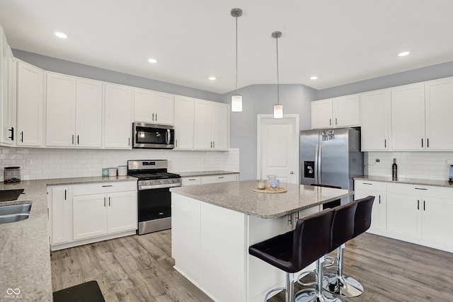 5812 Flat Hill Dr, Indianapolis, IN 46239 - kitchen with appliances with stainless steel finishes, decorative backsplash, a center island, light wood-style flooring, and recessed lighting