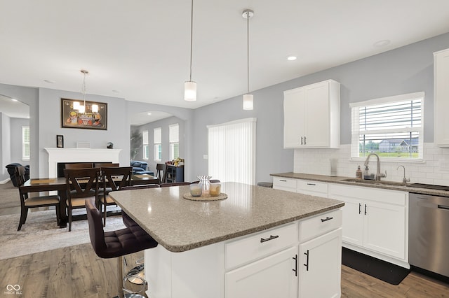 5812 Flat Hill Dr, Indianapolis, IN 46239 - kitchen featuring arched walkways, dishwasher, wood finished floors, light stone countertops, and a center island