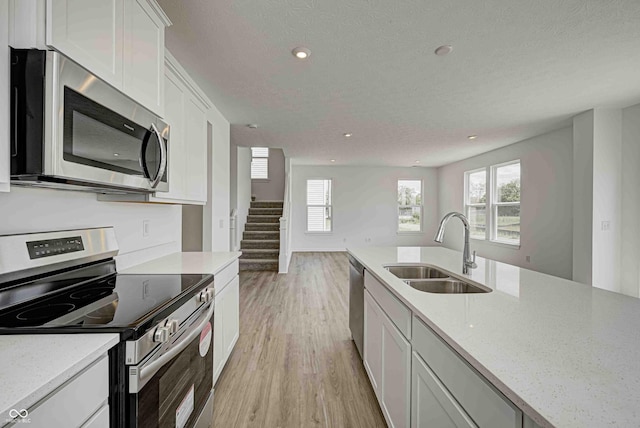 7501 Firecrest Ln, Camby, IN 46113 - kitchen with appliances with stainless steel finishes, light wood-style floors, white cabinetry, recessed lighting, and a textured ceiling
