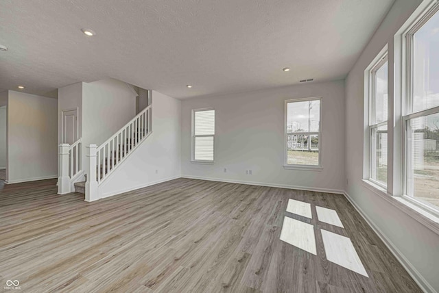 7501 Firecrest Ln, Camby, IN 46113 - unfurnished living room with wood finished floors, a textured ceiling, stairway, and recessed lighting