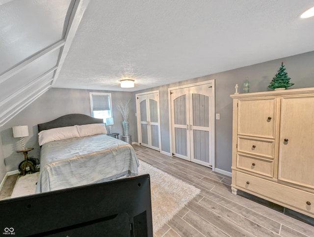 308 W Jefferson St, Kirklin, IN 46050 - bedroom with wood tiled floors, two closets, a textured ceiling, french doors, and vaulted ceiling