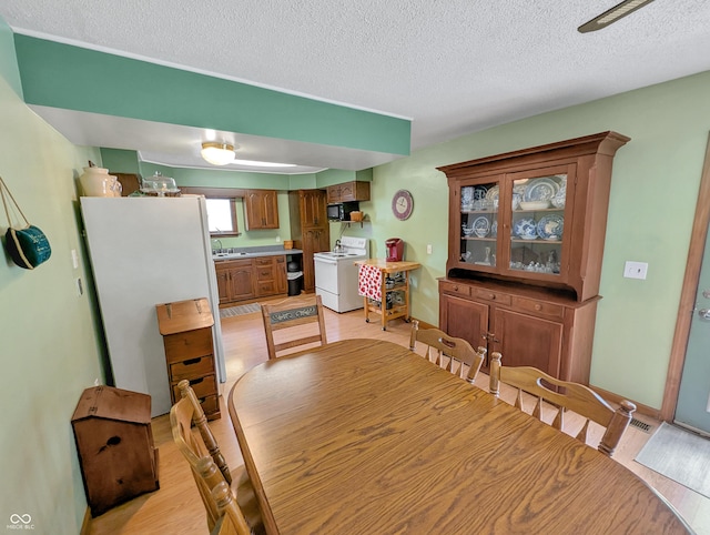 308 W Jefferson St, Kirklin, IN 46050 - dining area featuring light wood-style floors, a textured ceiling, and washer and clothes dryer
