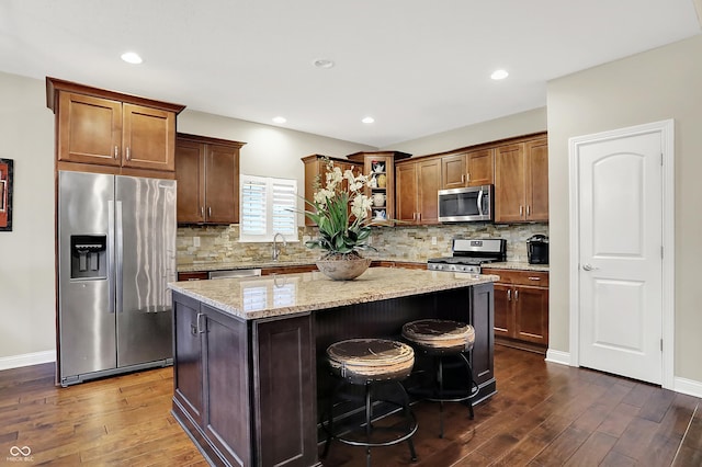 15410 Mission Hills Dr, Carmel, IN 46033 - kitchen featuring stainless steel appliances, dark wood finished floors, a kitchen island, light stone counters, and recessed lighting