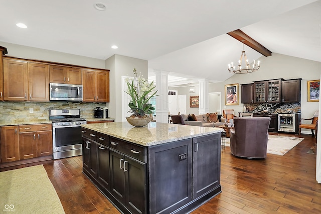 15410 Mission Hills Dr, Carmel, IN 46033 - kitchen featuring stainless steel appliances, ornate columns, dark wood-style flooring, decorative backsplash, and a kitchen island