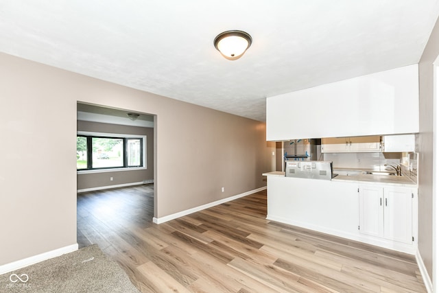 823 Rustic Rd, Anderson, IN 46013 - kitchen featuring light countertops, light wood finished floors, a peninsula, white cabinets, and open floor plan
