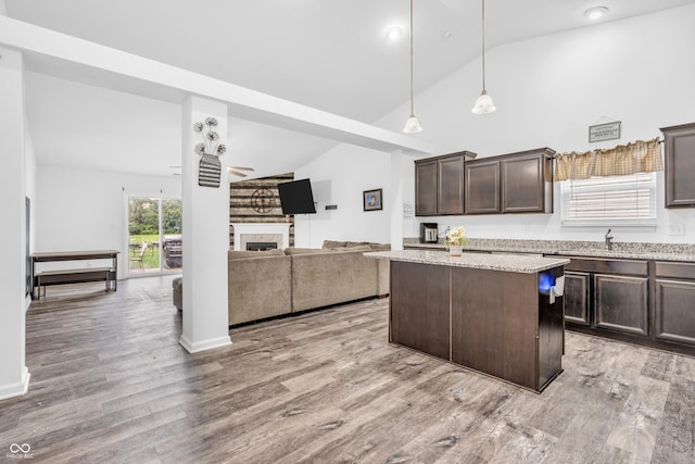 1181 S Aberdeen Dr, Franklin, IN 46131 - kitchen featuring dark brown cabinets, a center island, open floor plan, light wood-style floors, and decorative light fixtures