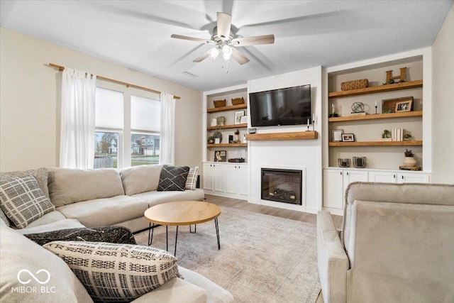 8547 Winton Pl, Pendleton, IN 46064 - living room featuring light wood-style flooring, a ceiling fan, a large fireplace, and built in shelves