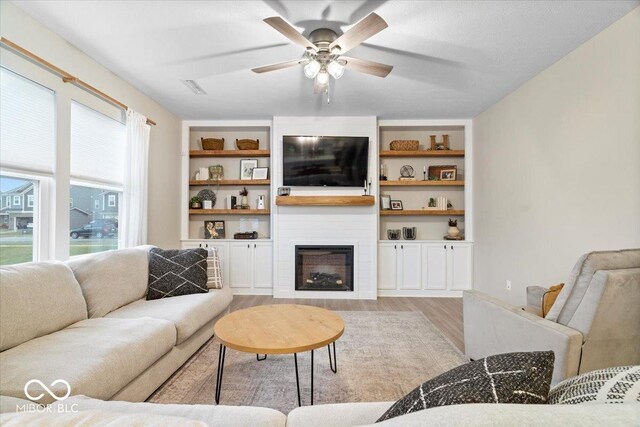 8547 Winton Pl, Pendleton, IN 46064 - living room with light wood-type flooring, a ceiling fan, a large fireplace, and built in shelves