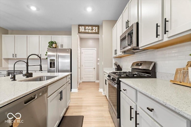 8547 Winton Pl, Pendleton, IN 46064 - kitchen featuring appliances with stainless steel finishes, light wood finished floors, decorative backsplash, light stone countertops, and white cabinetry