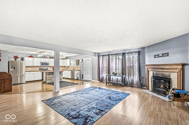 6259 Teacup Dr, Indianapolis, IN 46235 - living room with a textured ceiling, light wood-type flooring, healthy amount of natural light, and a fireplace